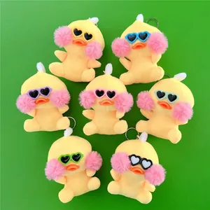 Seven yellow plush duck keychains with heart glasses arranged in a circle on green background