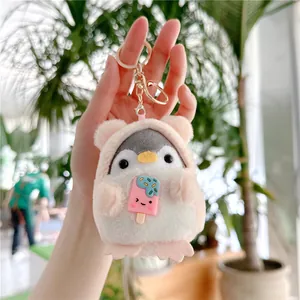 Close-up of plush penguin keychain in pink hood with gold metal ring and ice cream charm