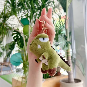 Detailed close-up of a green plush dinosaur keychain with a gold metal clasp and soft fur