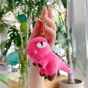 Detailed view of pink plush dinosaur keychain featuring golden metal lobster clasp
