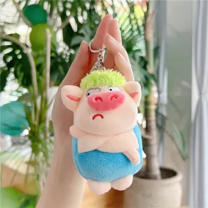 Detail of cute plush pig keychain with green hair and blue jacket on metal ring