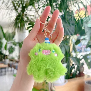 Close-up of fluffy green monster plush keychain with embroidery and gold ring