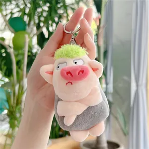 Detail of cute plush pig keychain with green hair and cross-armed pose in hand