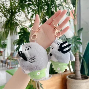 Grappige grijze pluche haai sleutelhanger met drietand en bloemendetails in hand