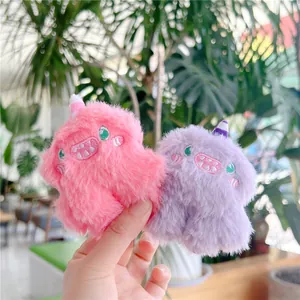 Close-up of pink and purple plush monster charms with soft fur and detailed embroidery