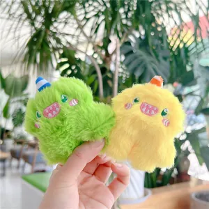 Close-up of bright green and yellow fuzzy monster plush keychains with cute embroidery