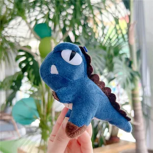 Detailed close-up of a blue plush dinosaur keychain with soft texture and white eyes