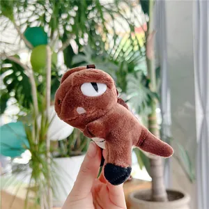 Close-up of a small brown plush dinosaur keychain with soft texture and detailed scales