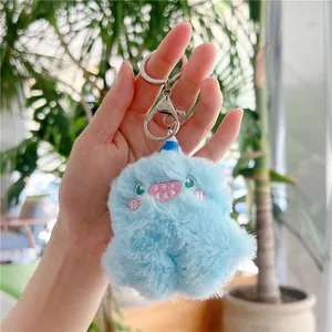 Detail of light blue plush monster keychain with embroidery held in hand