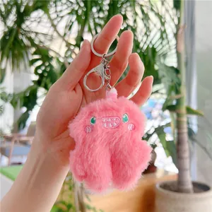 Close-up of pink plush monster keychain with fluffy texture and embroidered face details