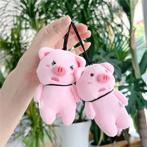 Close-up of two cute pink plush pig charms with different facial expressions