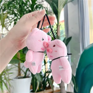 Close-up of pink plush pig charms with black lanyards and authentic product labels