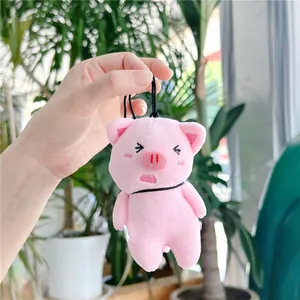 Close-up of a pink plush pig keychain with embroidered details and a black lanyard