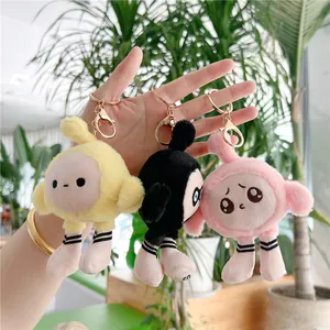 Trois porte-clés en peluche mignons en jaune noir et rose tenus à la main