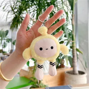 Gros plan d'un porte-clés en peluche jaune avec visage brodé et détails de jambes rayées