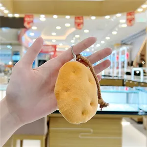 Detailed view of plush potato keychain with a braided strap and metal ring held in hand