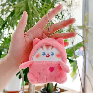 Detailopname van een roze pluche kattenhanger met zilveren sleutelhanger in de hand