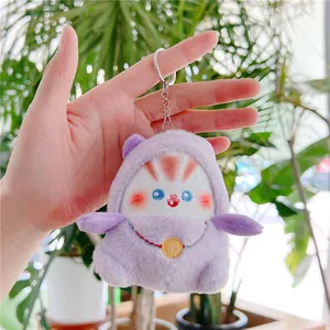 Detailopname van een pluchen katten-sleutelhanger met paarse hoodie en gouden munt