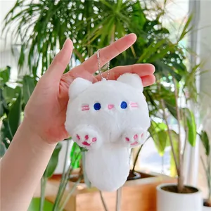 Detail van een witte pluche katten sleutelhanger met blauwe ogen en roze pootjes