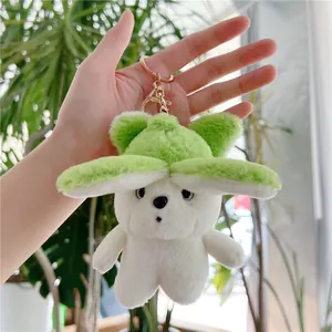 Close-up of fluffy white bear plush keychain with green leaf hat and rose gold clasp