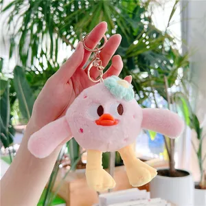 Détail du porte-clés canard en peluche rose avec pattes jaunes et fleur bleue