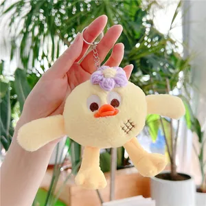 Gros plan du porte-clés oiseau en peluche jaune avec fleur violette et anneau argenté