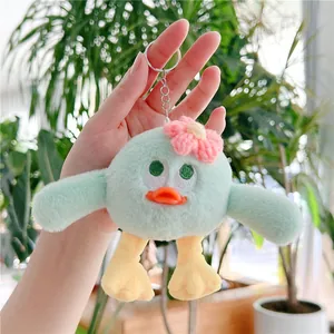Détail d'un porte-clés oiseau en peluche verte avec fleur rose et anneau métallique