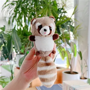 Detailed view of a cute plush raccoon keychain with a fluffy striped tail held in hand