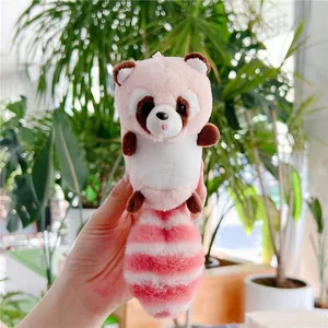 Close-up of cute plush raccoon keychain with a long striped fluffy tail held in hand