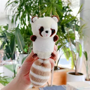 Close-up of a plush raccoon keychain accessory with soft faux fur held in hand