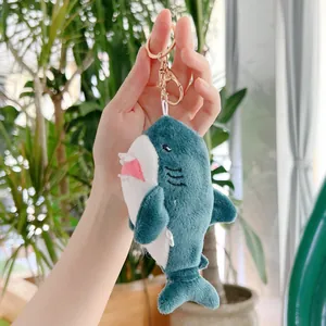 Dettaglio del portachiavi a squalo in peluche blu e bianco con anello dorato e moschettone