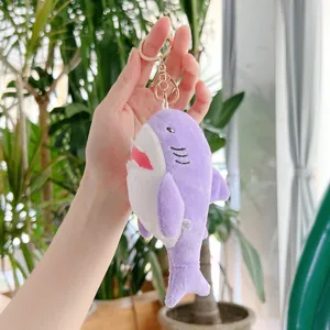 Primo piano di un portachiavi a forma di squalo viola in peluche con anello dorato