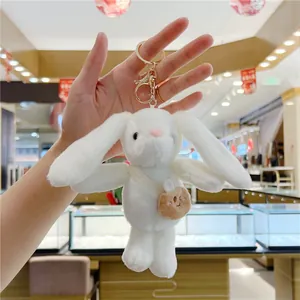 Close-up of white plush bunny keychain with brown carrot bag and gold metal clasp