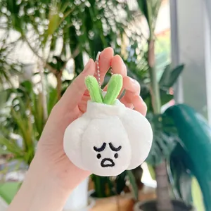 Hand holding cute plush garlic pendant with sad face embroidery and silver bead chain