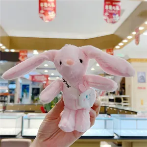Detailed shot of pink plush long-eared bunny keychain with a mini white crossbody bag