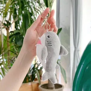 Dettaglio di un portachiavi a forma di squalo in peluche grigio con anello in metallo oro