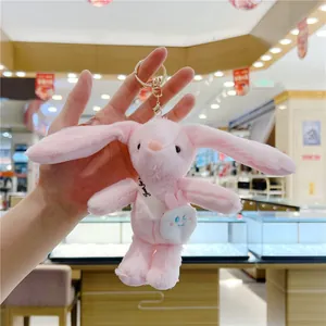 Detailed view of a soft pink plush bunny keychain with a mini white crossbody bag accessory