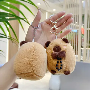 Cute brown capybara plush keychain set with bow tie and black beads in hand-held view