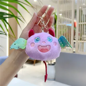 Détail du porte-clés chauve-souris en peluche violette avec ailes vertes et yeux étoiles