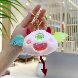 Détail d'un porte-clés monstre en peluche rose avec broderie d'étoiles sur les ailes