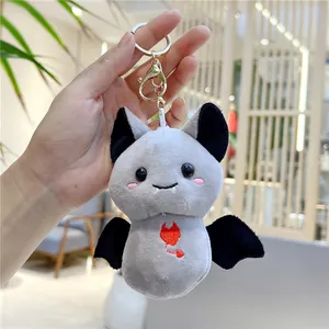 Close-up of cute grey plush bat keychain with red heart embroidery and golden clip