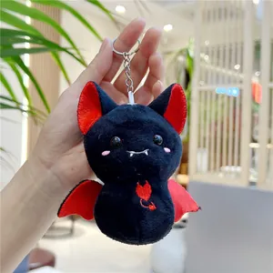 Detail of plush bat keychain with red embroidery and metal ring held by hand
