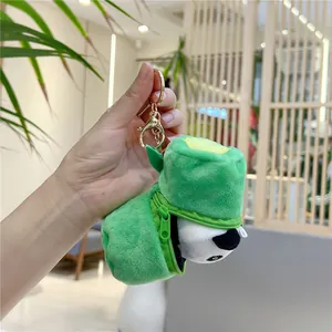 Detailed view of panda plush inside a green bamboo shoot bag with gold keychain