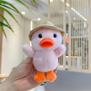 Dettaglio del ciondolo a forma di anatra rosa in peluche con cappellino di paglia in mano