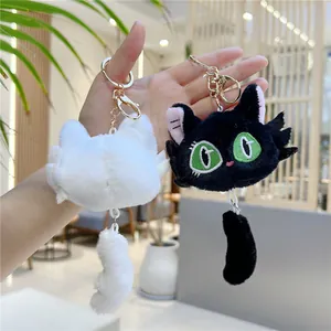 Close-up of cute plush cat keychains in black and white with soft fur and golden hooks