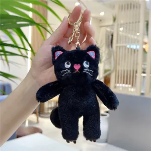 Macro shot of black plush cat keychain with pink embroidery and golden metal clasp