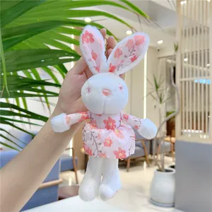 Close-up of plush bunny keychain with pink floral dress and metal hanging buckle