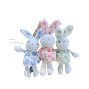 Three plush bunny keychains wearing blue, pink, and green floral dresses on white background