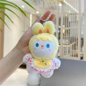 Close-up of white rabbit plush keychain with yellow hood and carrot embroidery detail