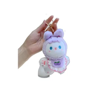 Cute purple plush rabbit keychain with cherry lace bib accessory in hand view